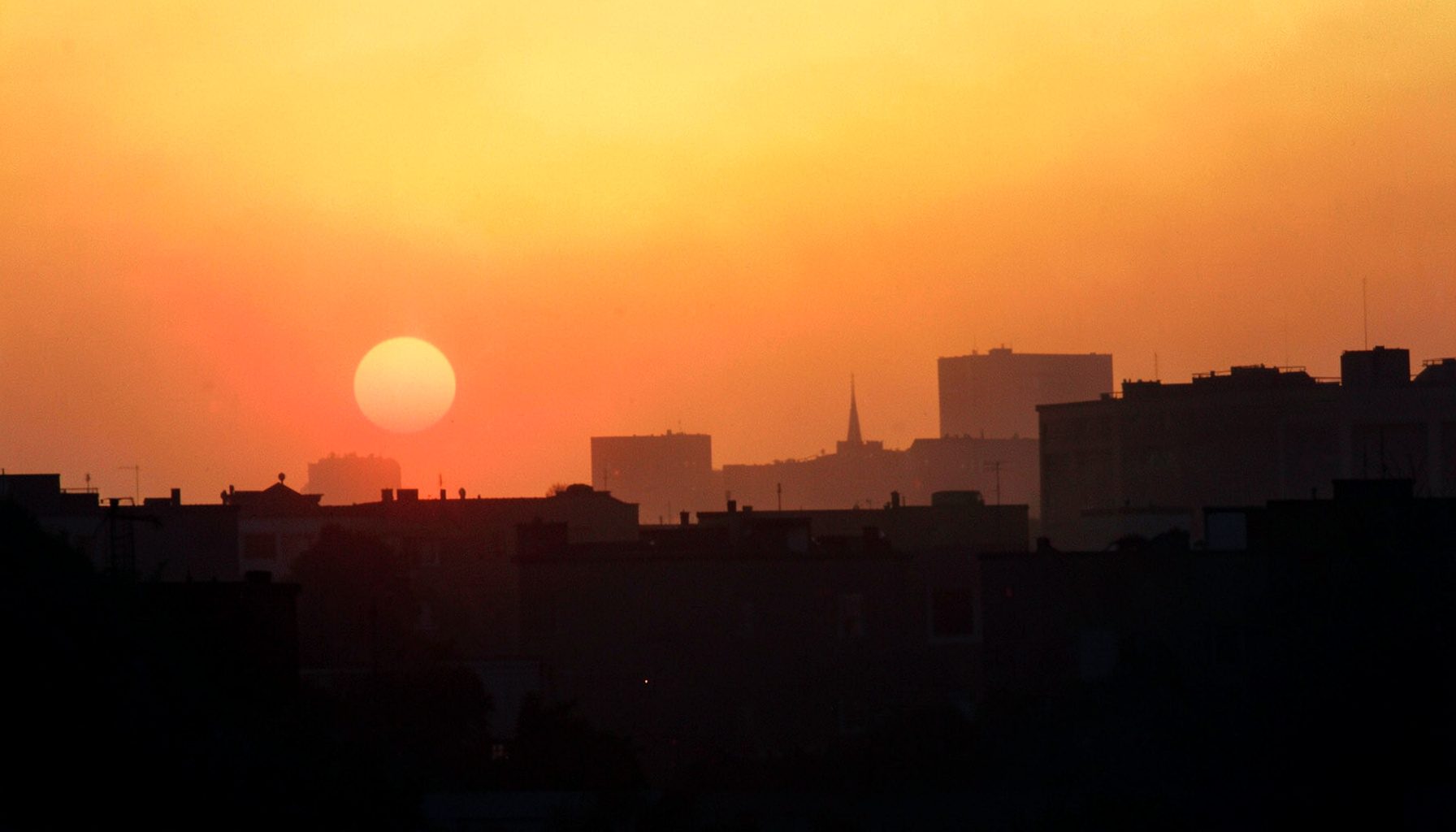 黄金色の夕日を浴びた街並みのシルエット、オレンジと深い青のグラデーションが広がる穏やかな風景