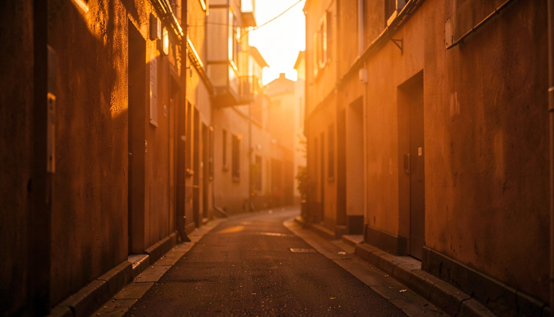 暖かな夕暮れの光に照らされた静かな路地、柔らかな琥珀色の光が壁に映り込む落ち着いた雰囲気の風景